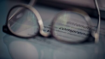 Des lunettes sur un écran d'ordinateur flou pour illustrer la formation FALC (Facile à lire et à comprendre)